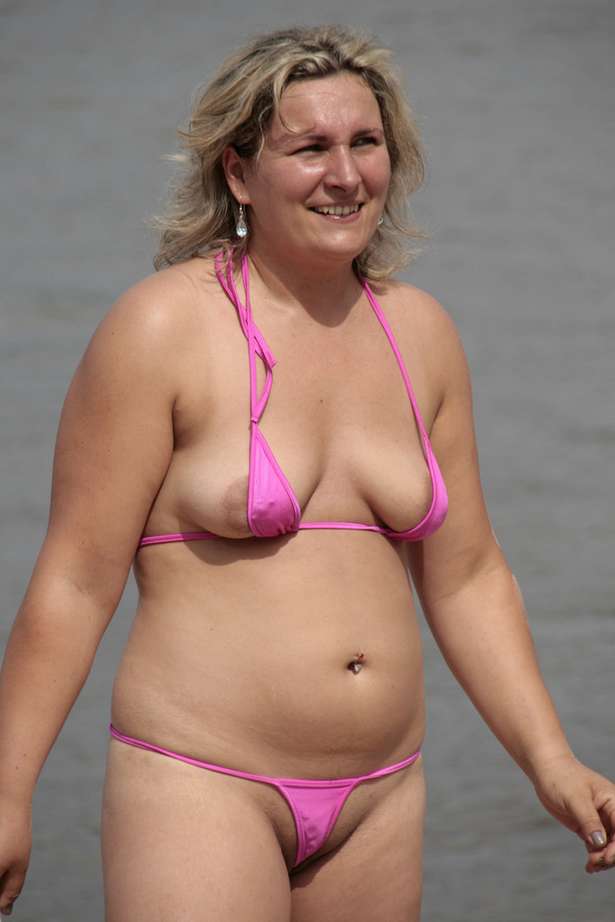 Une mature blonde joue sur la plage avec son mini bikini...
